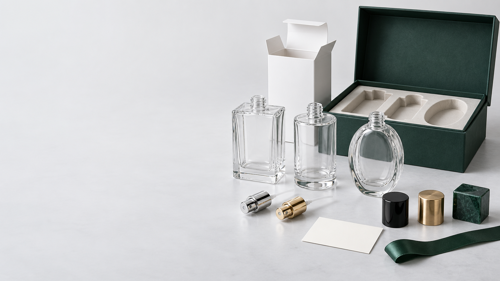 Concept presentation of empty glass perfume bottles, separate caps and spray pumps, and coordinated gift packaging
