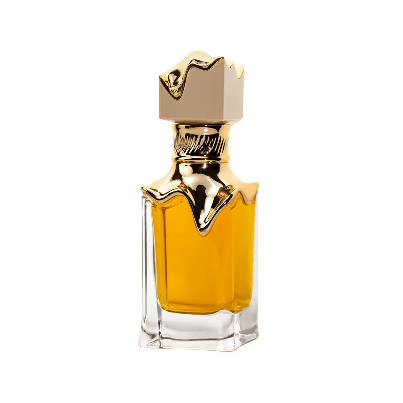 Single clear perfume bottle with sculptural gold-accent cap